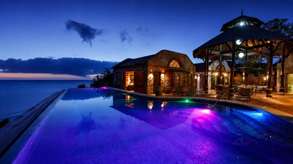 Night view of a villa, gazebo, and illuminated pool